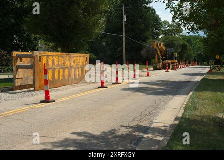 L'invention concerne un caisson de tranchée et un excavateur pour des travaux de remplacement de conduites d'eau dans une rue de ville avec des cônes de circulation pour la fermeture de voies Banque D'Images