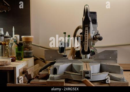 Station de travail du bois bien organisée avec un dispositif de scierie électrique et divers outils soigneusement disposés sur l'établi créant un espace de travail efficace pour les amateurs de menuiserie Banque D'Images