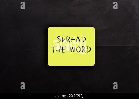 Un autocollant jaune avec les mots Spread the Word écrit dessus. L'autocollant est placé sur un fond noir Banque D'Images