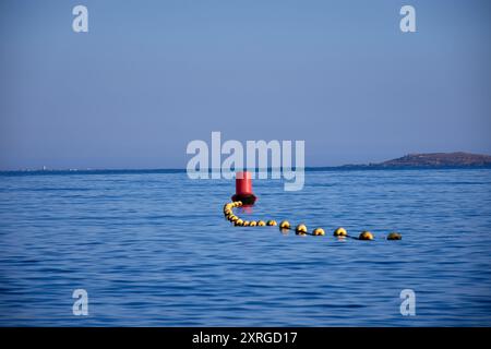 la zone de baignade désignée sur une plage, clairement marquée par une ligne de bouées jaunes surmontées d'une plus grande bouée rouge à l'extrémité. Le bu jaune Banque D'Images