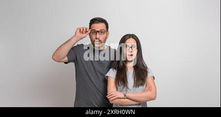 Portrait de jeune couple surpris avec la bouche ouverte regardant la caméra et posant sur fond isolé. Homme étonné et femme portant des lunettes R Banque D'Images