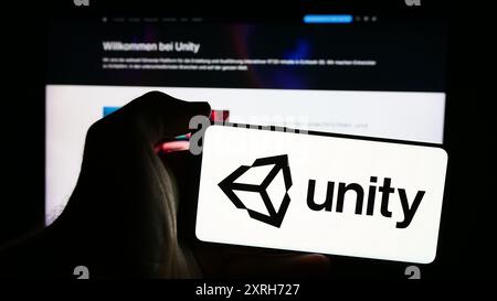 Personne tenant un smartphone avec le logo de la société américaine de jeux vidéo Unity Software Inc en face du site Web. Concentrez-vous sur l'affichage du téléphone. Banque D'Images