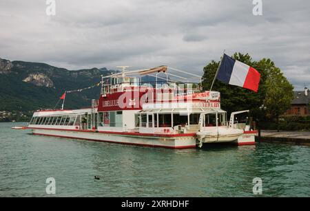 Lac d'Annecy, France - 24 août 2015 : bateau-restaurant de croisière avec pavillon français au coucher du soleil. Annecy Lake Boat Company propose des croisières guidées Banque D'Images