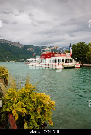 Lac d'Annecy, France - 24 août 2015 : bateau-restaurant de croisière avec pavillon français au coucher du soleil. Annecy Lake Boat Company propose des croisières guidées Banque D'Images