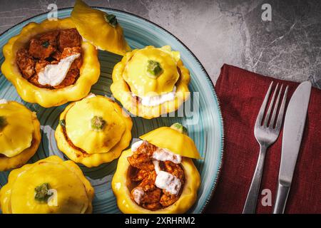 Dinde cuite dans la citrouille avec du fromage. Quelques citrouilles farcies sur une assiette turquoise. Gros plan. Photo de haute qualité Banque D'Images