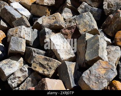 Une collection de briques irrégulières dans des textures et des couleurs variées empilées ensemble à la lumière du jour. Banque D'Images