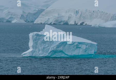 Antarctique forme unique d'iceberg glace blanche et bleue et neige avec montagnes couvertes en arrière-plan. Photographie de paysage incroyable couleurs douces Banque D'Images