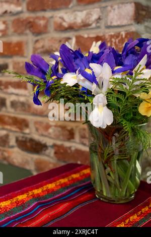 Issaquah, Washington, États-Unis. Bouquet de fleurs d'iris assis sur une table contre un mur de briques rouges. Banque D'Images