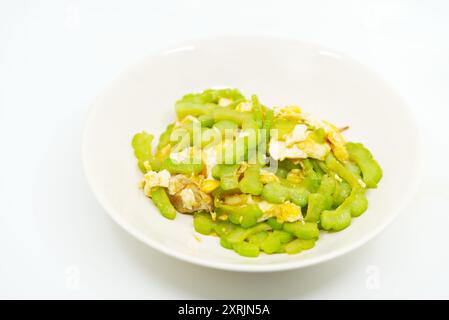 Gros plan image de nourriture de melon amer sautés avec oeuf de poule et sauce d'huître dans un plat blanc cassé sur fond blanc, menu alimentaire sain asiatique. Banque D'Images