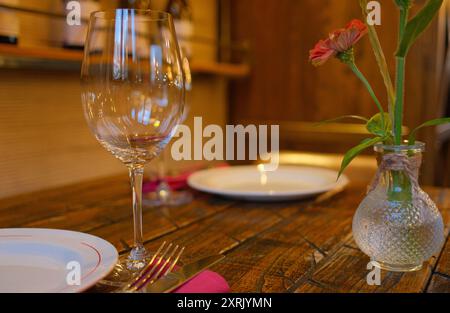 Table élégante dans un restaurant confortable avec verre à vin vide, assiette blanche et couverts en argent sur une table en bois rustique Banque D'Images