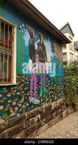 Dresde, Allemagne - 7 octobre 2023 : deux personnages tiennent une cage à oiseaux dans une murale urbaine Banque D'Images