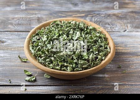 Feuilles d'origan séchées dans un bol en bois sur une table en bois Banque D'Images