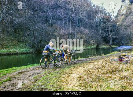 Deux cyclistes masculins s'occupant de leurs vélos sur un chemin boueux près de River Dove, Dovedale, parc national Peak District, Derbyshire, Angleterre, Royaume-Uni 1956 Banque D'Images