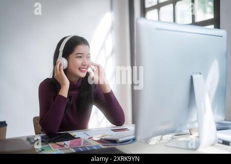 Graphiste femmes freelance portant casque à écouter de la musique à la détente après avoir esquissé la marque de logo et travailler à la conception sur le graphique Banque D'Images