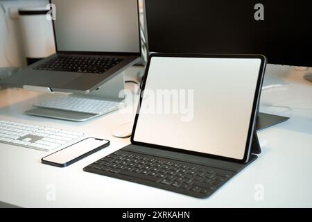 Table de bureau avec dispositifs électroniques. Maquette d'écran propre pour ordinateur portable et smartphone. Banque D'Images