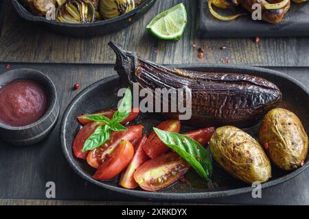 Aubergines entières cuites au four et pommes de terre avec tomates fraîches et basilic Banque D'Images