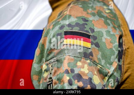 11 août 2024 : un soldat de la Bundeswehr en uniforme de camouflage avec le drapeau allemand cousu sur des stands devant le drapeau russe. Image symbolique des relations tendues entre l'Allemagne et la Russie dans un contexte militaire et géopolitique. PHOTOMONTAGE *** Ein Bundeswehrsoldat in TarnUniform mit aufgenähter Deutschlandflagge steht vor der russischen Flagge. Symbolbild angespannte Beziehungen zwischen Deutschland und Russland im militärischen und geopolitischen Kontext. FOTOMONTAGE Banque D'Images