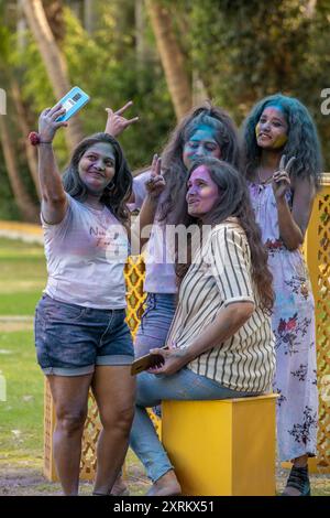 Un groupe de jeunes femmes célébrant le festival Holi avec de la poudre colorée, prenant un selfie dans un parc Banque D'Images
