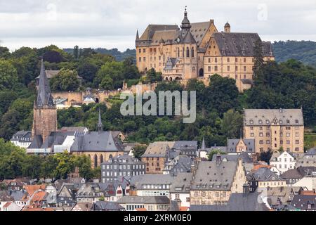 Marburg, Allemagne. 09 août 2024. Le château de Marburg, également connu sous le nom de Landgrave's Castle Marburg, s'élève au-dessus de la ville. Vue du sud-est avec une vue sur la vieille ville (ville haute) avec l'église paroissiale luthérienne (à gauche) et le 'Old District court' (à droite). Il est né comme un château au XIe siècle et a été converti en palais résidentiel par les Landgraves de Hesse au XIIIe siècle. Depuis 1981, le château abrite le musée d'histoire de l'art de l'Université Philipps de Marbourg. Crédit : Christian Lademann/dpa/Alamy Live News Banque D'Images