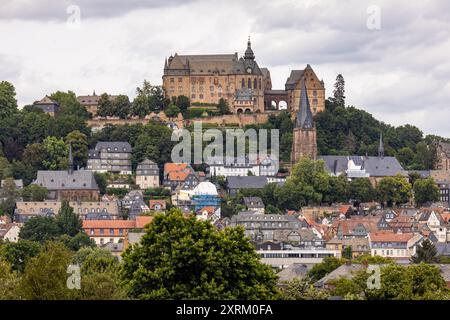 Marburg, Allemagne. 09 août 2024. Le château de Marburg, également connu sous le nom de Landgrave's Castle Marburg, s'élève au-dessus de la ville. Vue générale du sud avec vue sur la vieille ville (ville haute) avec Kugelkirche (à droite) et l'église paroissiale luthérienne (juste en dessous du château). Il est né comme un château au XIe siècle et a été converti en palais résidentiel par les Landgraves de Hesse au XIIIe siècle. Depuis 1981, le château abrite le musée d'histoire de l'art de l'Université Philipps de Marbourg. Crédit : Christian Lademann/dpa/Alamy Live News Banque D'Images