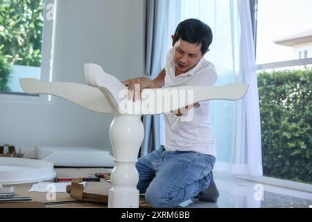 Homme asiatique assemblant des meubles de table blancs à la maison Banque D'Images