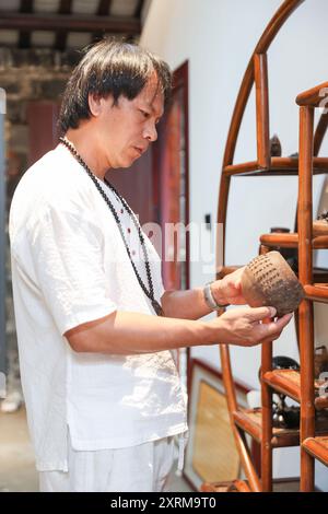 (240811) -- HAIKOU, 11 août 2024 (Xinhua) -- Wu Mingju organise des œuvres de sculpture de coquilles de noix de coco dans un atelier à Haikou, dans la province de Hainan, dans le sud de la Chine, le 9 août 2024. La sculpture de coquille de noix de coco, une forme d'art qui implique la création de dessins à l'aide d'outils de sculpture sur la coquille dure d'une noix de coco, a été répertoriée comme l'un des patrimoines culturels immatériels nationaux en 2008. Wu Mingju, un héritier de la sculpture de coquille de noix de coco, s'est engagé à l'héritage et à la promotion de cet art ancien et complexe depuis 33 ans en explorant l'innovation technique, en mettant en place des cours de sculpture de coquille de noix de coco dans les écoles Banque D'Images