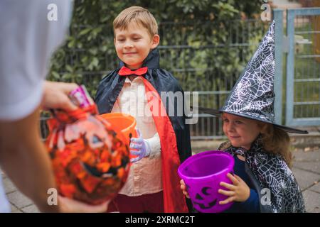 Adorable garçon et fille habillé en sorcière et dracula avec des seaux de citrouilles. Automne. Banque D'Images