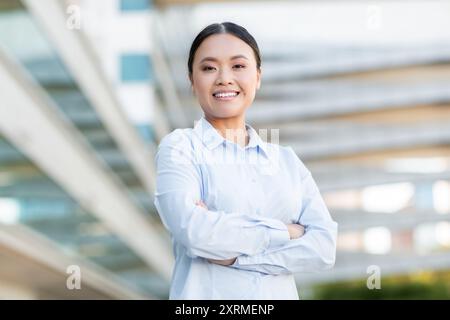 Sourire jeune femme debout avec les bras croisés à l'extérieur Banque D'Images