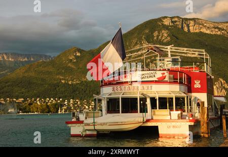 Lac d'Annecy, France - 24 août 2015 : bateau-restaurant de croisière avec pavillon français au coucher du soleil. Annecy Lake Boat Company propose des croisières guidées Banque D'Images