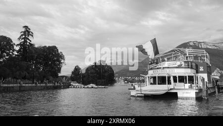 Lac d'Annecy, France - 24 août 2015 : bateau-restaurant de croisière avec pavillon français sur le lac. Annecy Lake Boat Company propose des croisières guidées. Noir blanc Banque D'Images