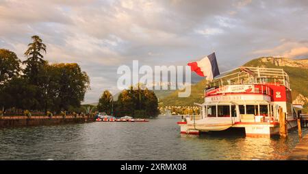 Lac d'Annecy, France - 24 août 2015 : bateau-restaurant de croisière avec pavillon français au coucher du soleil. Annecy Lake Boat Company propose des croisières guidées Banque D'Images