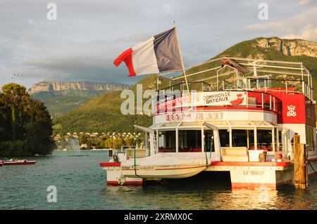 Lac d'Annecy, France - 24 août 2015 : bateau-restaurant de croisière avec pavillon français au coucher du soleil. Annecy Lake Boat Company propose des croisières guidées Banque D'Images