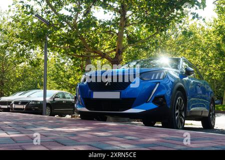 Bucarest, Roumanie - 22 juillet 2024 : Peugeot 2008 voiture bleue dans un parking le long d'une passerelle pavée Banque D'Images