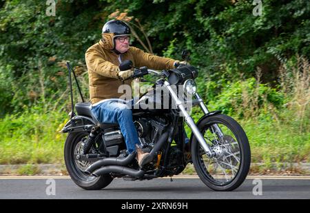 Potterspury, Northants, UK - 11 août 2024 : homme conduisant une Harley Davidson Wide Glide moto voyageant sur une route britannique Banque D'Images