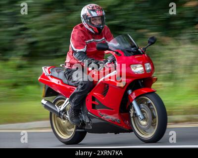 Potterspury, Northants, Royaume-Uni - 11 août 2024 : homme conduisant une Honda VFR750F rouge 1997 voyageant sur une route britannique Banque D'Images