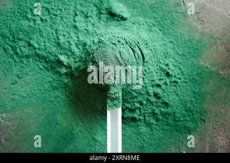 Poudre de spiruline verte dans une tasse à mesurer en plastique, vue de dessus Banque D'Images