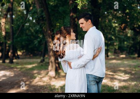 guy et une fille marchent le long des chemins d'un parc forestier entre de grands arbres Banque D'Images