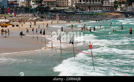 Plage Charles clore avec drapeaux noirs à tel Aviv. Les gens nagent malgré les grosses vagues Banque D'Images