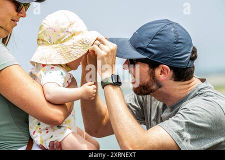 C'est comment ne pas mettre de lunettes de soleil sur un bébé. Maman tient bon pendant que papa travaille très dur pour trouver le petit nez du bébé. Après cela, assurez-vous qu'ils vont tomber. Banque D'Images