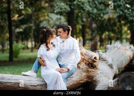 guy et une fille marchent le long des chemins d'un parc forestier entre de grands arbres Banque D'Images