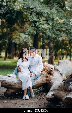 guy et une fille marchent le long des chemins d'un parc forestier entre de grands arbres Banque D'Images