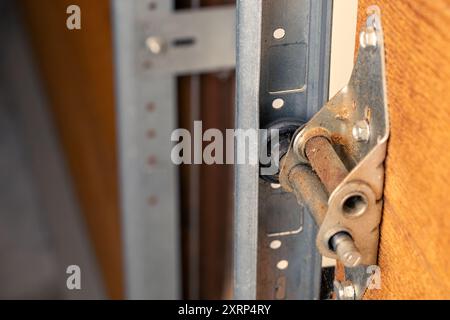 Gros plan de la charnière de porte de garage et du rouleau sur la porte en bois, mise au point sélective. Banque D'Images