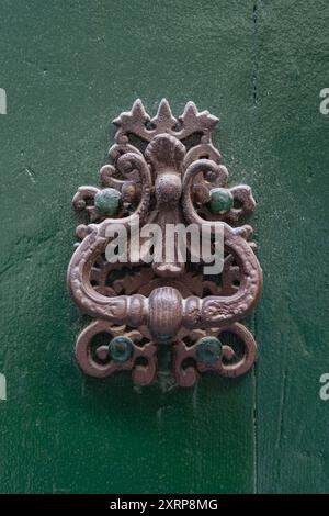 Vue rapprochée de belle frappe de porte en laiton vintage isolé sur une ancienne porte en bois vert, Anduze, Gard, France Banque D'Images