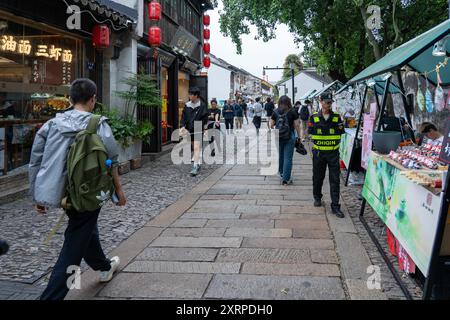 Suzhou, Chine - 11 juin 2024 : Une rue pavée bordée de magasins et de vendeurs à Suzhou, Chine. Banque D'Images