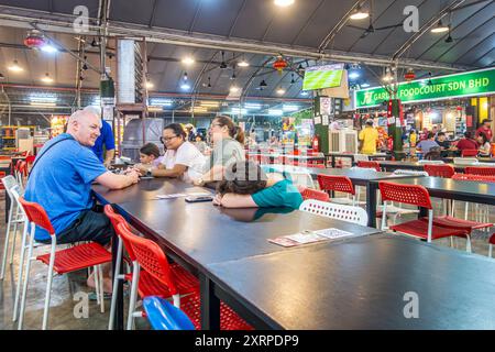 Une famille assise à une table prête à manger à JJ Garden Food court à Tanjung Bungah, Penang, Malaisie Banque D'Images