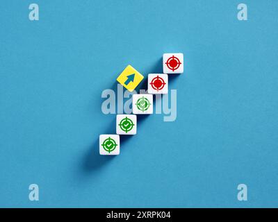 Rangée de cubes illustrant le concept d'atteinte des objectifs de l'entreprise, avec un cube jaune affichant une flèche vers le haut symbolisant la progression et la réussite. KPI ke Banque D'Images