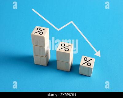 Flèche blanche pointant vers le bas au-dessus des cubes en bois montrant le symbole de pourcentage, représentant la diminution du taux d'intérêt ou du taux hypothécaire. Banque D'Images