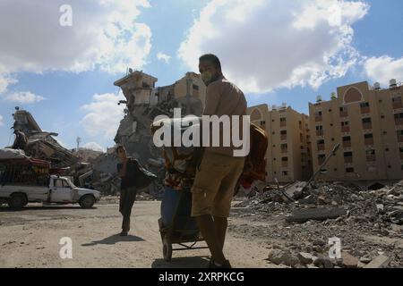 Les Palestiniens vivant dans la région migrent vers le district d'Al Mawasi, la partie ouest de la ville avec leurs biens suite à l'avertissement d'évacuation de l'armée israélienne dans la région de Hamad à Khan Yunis, Gaza, le 11 août 2024. Israël a élargi les ordres d'évacuation à Khan Younis, dans le sud de la bande de Gaza, du jour au lendemain, forçant des dizaines de milliers de résidents palestiniens et de familles déplacées à partir dans l'obscurité alors que les explosions des bombardements de chars se sont répercutées autour d'eux. L’armée israélienne a déclaré qu’elle attaquait des militants du groupe Hamas, qui administrait Gaza avant la guerre, qui utilisaient ces zones Banque D'Images