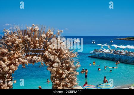 Arche surplombant une scène de plage sereine avec parasols et nageurs à la plage de la Garoupe, Cap d'Antibes, Côte d'Azur, France Banque D'Images