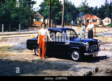 Souriante femme propriétaire de Ford Prefect car dans la zone de construction de nouveaux logements de banlieue, Royaume-Uni 1956 Banque D'Images